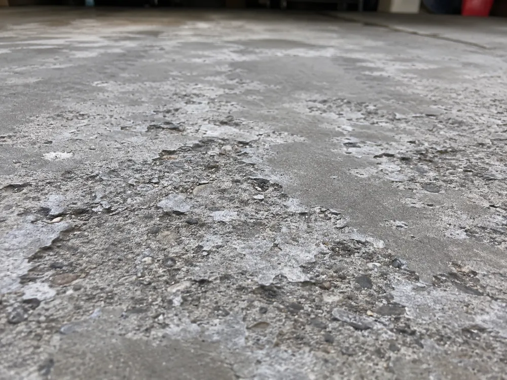 Close-up of concrete surface damage caused by repeated freeze-thaw cycles